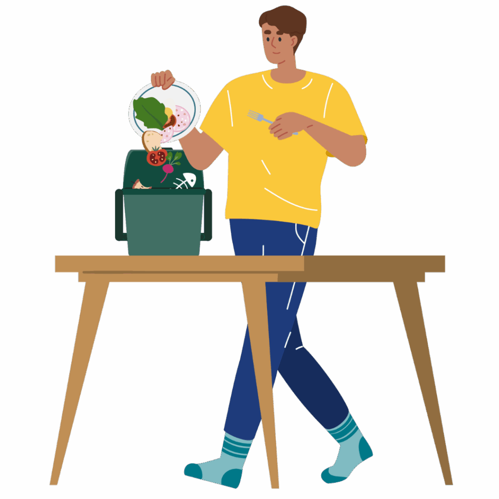 A person in a yellow shirt and blue pants stands at a table, scraping leftover food from a plate into a green kitchen caddy filled with food scraps.