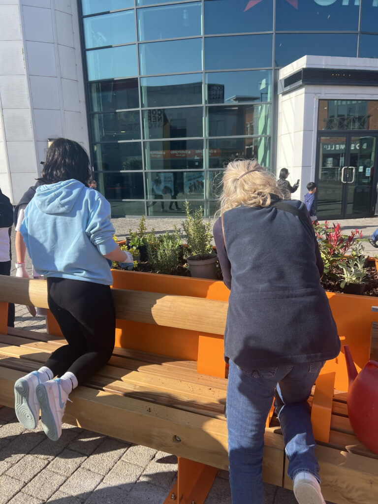 Teenagers planting plants in an orange planter