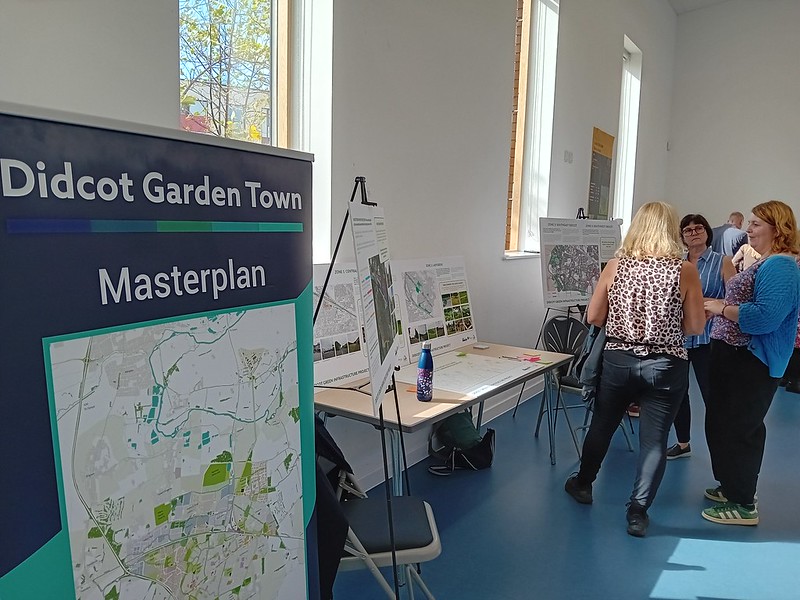 People in the distance with close up on board showing Didcot Garden Town masterplan