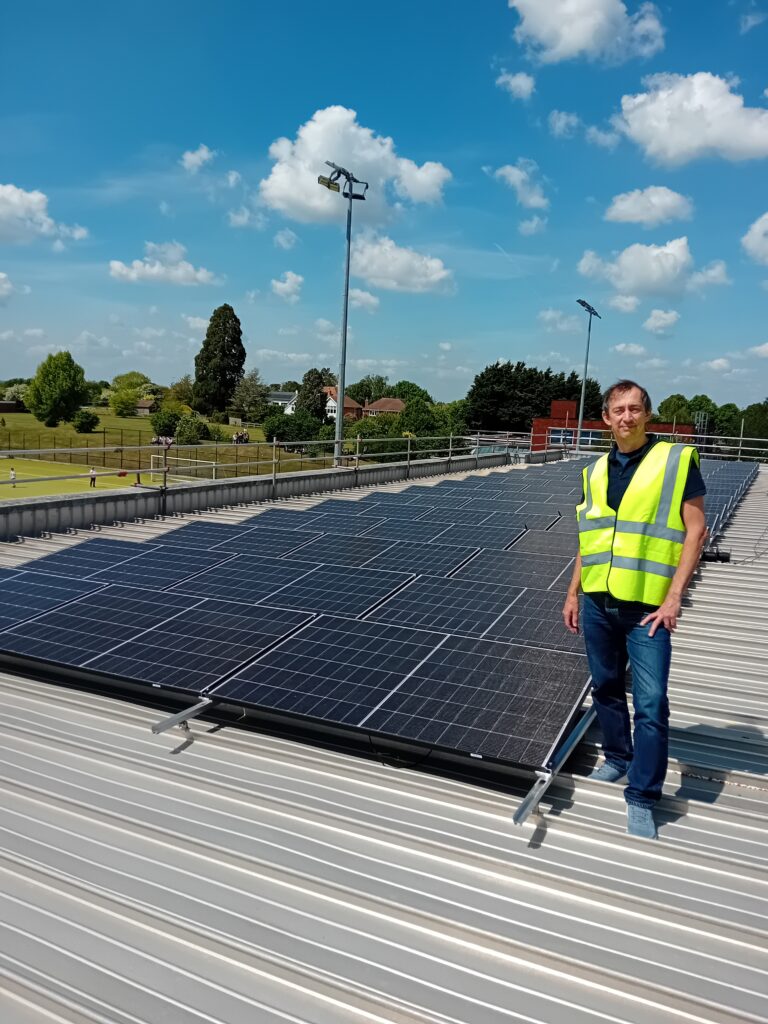 Cllr Pieter-Paul Barker on the roof of Thame Leisure Centre in front of an installation of solar panels.