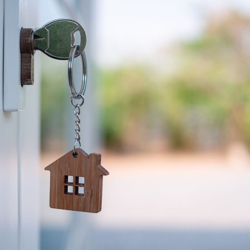 A key in the door with a small wooden house on the key fob