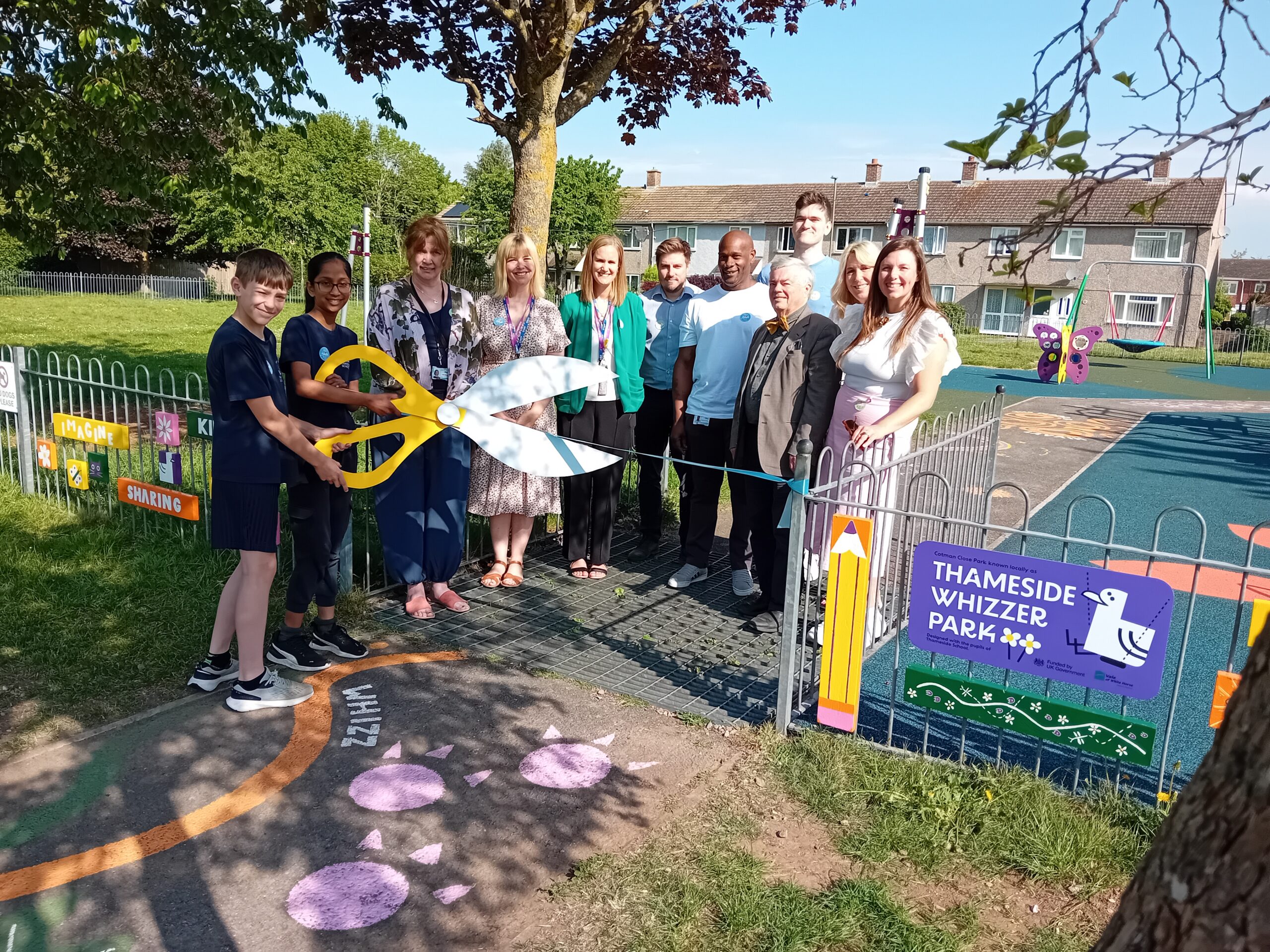 Collection of people around ribbon with oversized scissors