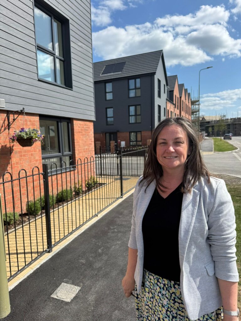 A woman stands in front of houses on a new housing estate on a sunny day