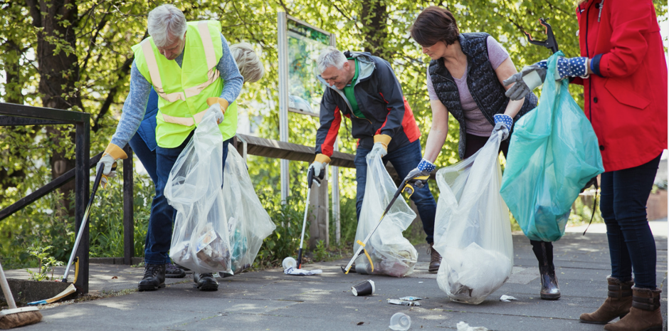 A group of people pick up litter and place it into clear plastic bags